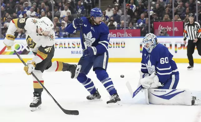 Toronto Maple Leafs goaltender Joseph Woll (60) makes a stop in front of Vegas Golden Knights Ivan Barbashev (49) as Leafs Chris Tanev (8) looks for the rebound during first period NHL hockey action in Toronto, on Wednesday, November 20, 2024. (Chris Young/The Canadian Press via AP)