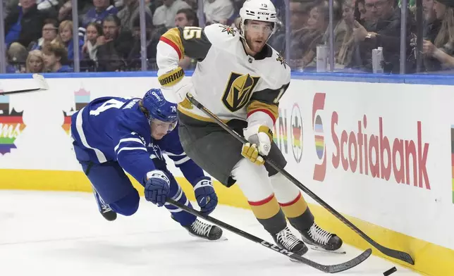 Vegas Golden Knights Noah Hanifin (15) and Toronto Maple Leafs Bobby McMann (74) battle for the puck during second period NHL hockey action in Toronto, on Wednesday, November 20, 2024. (Chris Young/The Canadian Press via AP)