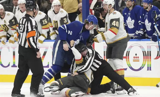 A referee intervenes as Toronto Maple Leafs Simon Benoit (2) fights with Vegas Golden Knights Zach Whitecloud (2) during second period NHL hockey action in Toronto, on Wednesday, November 20, 2024. (Chris Young/The Canadian Press via AP)