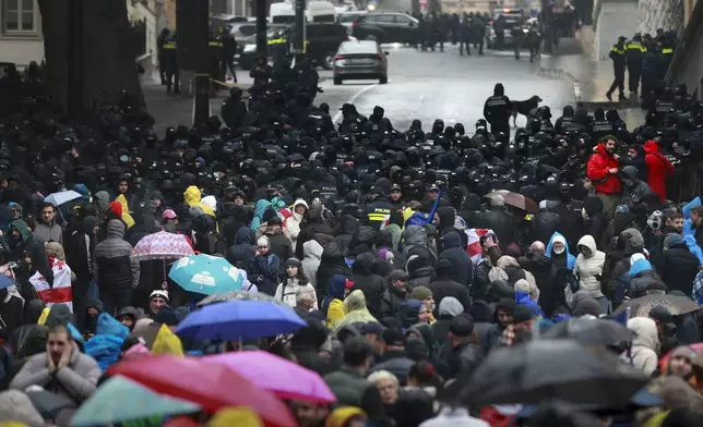 Police block protesters gathered in a street during a rally to demand new parliamentary elections in the country, near the Parliament's building in Tbilisi, Georgia, Monday, Nov. 25, 2024. (AP Photo/Zurab Tsertsvadze)