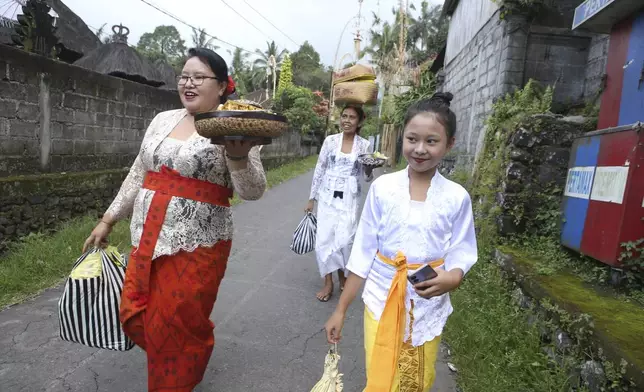 Kadek Krisni, left, walks with her daughter Ketut Nita Wahyuni, 11, to participate in a Hindu ceremony at Geriana Kauh village, Karangasem, Bali, Indonesia, Wednesday, Nov. 20, 2024. (AP Photo/Firdia Lisnawati)