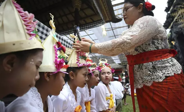 Kadek Krisni fixes an incense stick on the headgear of her daughter Ketut Nita Wahyuni, 11, before a Hindu ritual at Geriana Kauh village, Karangasem, Bali, Indonesia on Wednesday, Nov. 20, 2024. (AP Photo/Firdia Lisnawati)