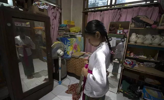 Ketut Nita Wahyuni, 11, prepares for school at her home in Geriana Kauh village, Karangasem, Bali, Indonesia on Thursday, Nov. 21, 2024. (AP Photo/Firdia Lisnawati)