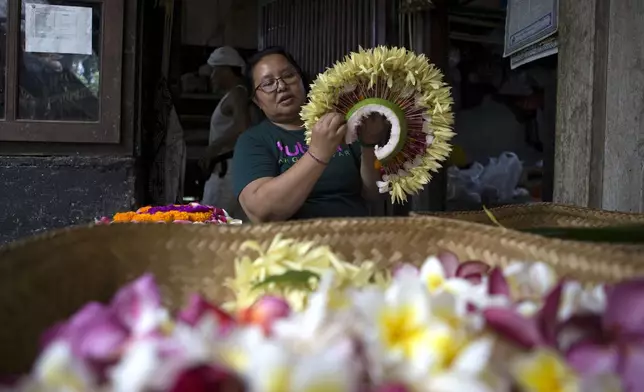 Kadek Krisni prepares a headgear for her daughter to participate in Rejang Pucuk at Geriana Kauh village, Karangasem, Bali, Indonesia on Thursday, Nov. 21, 2024. (AP Photo/Firdia Lisnawati)