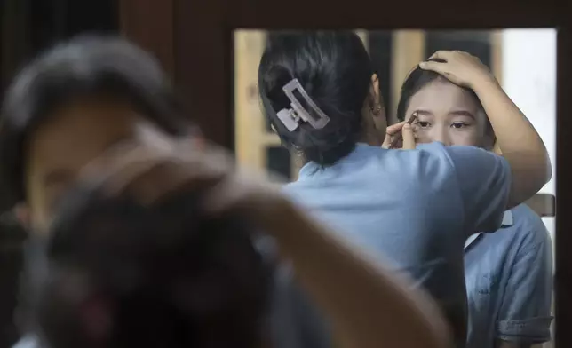 Intan Wahyuni applies makeup for her younger sister Ketut Nita Wahyuni, 11, before participating in Rejang Pucuk Hindu rituals at Geriana Kauh village, Karangasem, Bali, Indonesia on Thursday, Nov. 21, 2024. (AP Photo/Firdia Lisnawati)