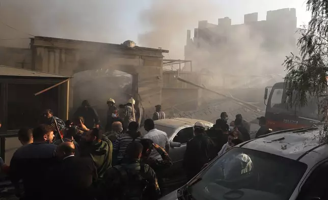 Security officers and rescuers gather at a destroyed building hit in an Israeli airstrike in Damascus, Syria, Thursday, Nov. 14, 2024. (AP Photo/Omar Sanadiki)