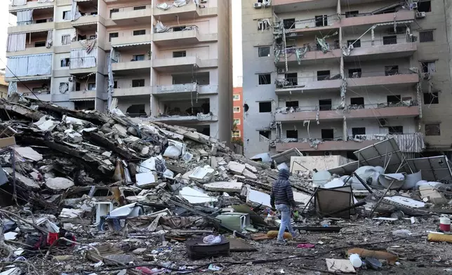 A man passes in front of destroyed buildings that were hit in an Israeli airstrike in Dahiyeh, in the southern suburb of Beirut, Lebanon, Thursday, Nov. 14, 2024. (AP Photo/Hussein Malla)