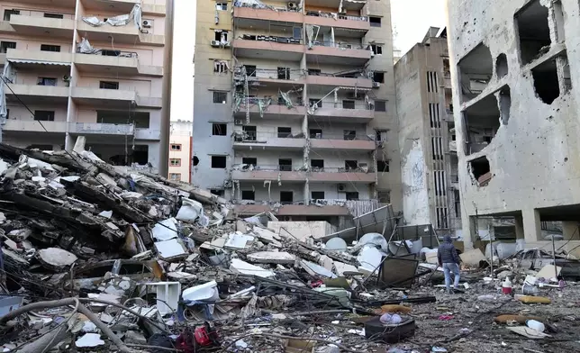 A man passes in front of destroyed buildings that were hit in an Israeli airstrike in Dahiyeh, in the southern suburb of Beirut, Lebanon, Thursday, Nov. 14, 2024. (AP Photo/Hussein Malla)