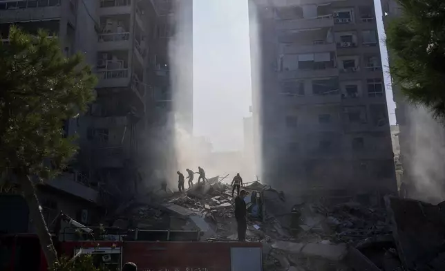 Civil defense workers extinguish a fire as smoke rises from the site of an Israeli airstrike in Tayouneh, Beirut, Lebanon, Friday, Nov. 15, 2024. (AP Photo/Hassan Ammar)