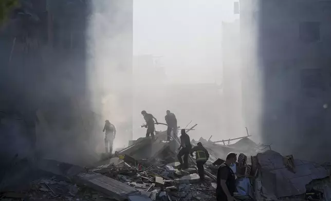 Civil defense workers extinguish a fire as smoke rises from the site of an Israeli airstrike in Tayouneh, Beirut, Lebanon, Friday, Nov. 15, 2024. (AP Photo/Hassan Ammar)