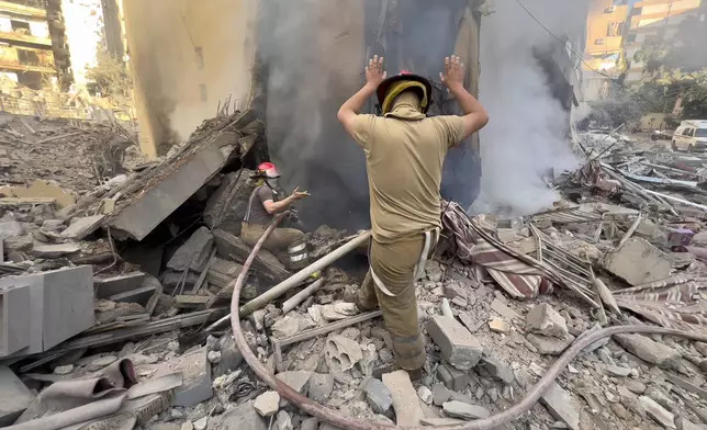 Firefighters try to extinguish a fire as smoke rises from a destroyed building that was hit in an Israeli airstrike in Dahiyeh, in the southern suburb of Beirut, Lebanon, Thursday, Nov. 14, 2024. (AP Photo/Hussein Malla)