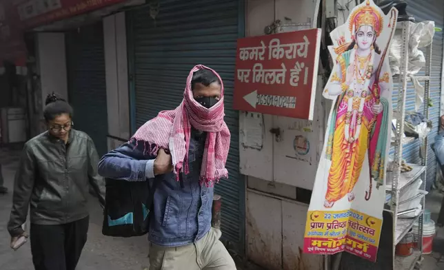 A office goer walks wearing a face mask amidst a thick layer of smog as air pollution shoots up in New Delhi, India, Monday, Nov. 18, 2024. (AP Photo/Manish Swarup)