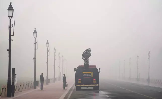 A Delhi government vehicle sprinkles water to control air pollution amidst thick Layer of smog in New Delhi, India, Monday, Nov. 18, 2024. (AP Photo/Manish Swarup)