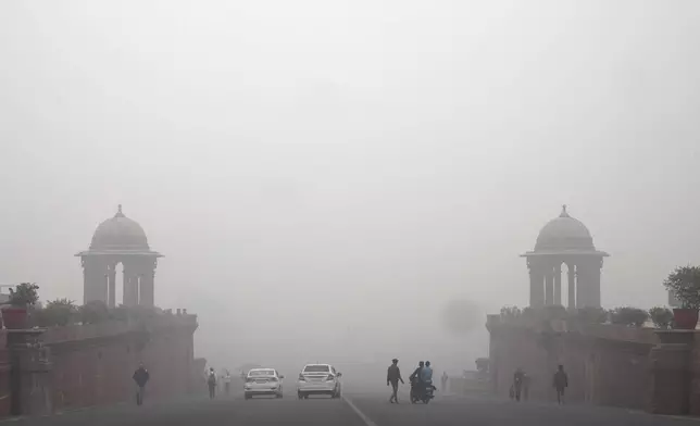 Office goers walk wearing a face mask amidst a thick layer of smog as air pollution shoots up in New Delhi, India, Monday, Nov. 18, 2024. (AP Photo/Manish Swarup)