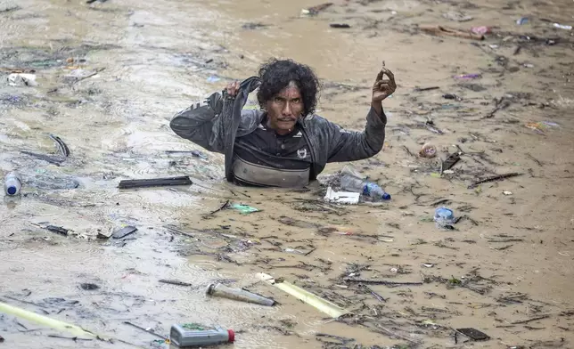 A man wades through flood water following heavy downpours in Medan, North Sumatra, Indonesia, Wednesday, Nov. 27, 2024. (AP Photo/Binsar Bakkara)