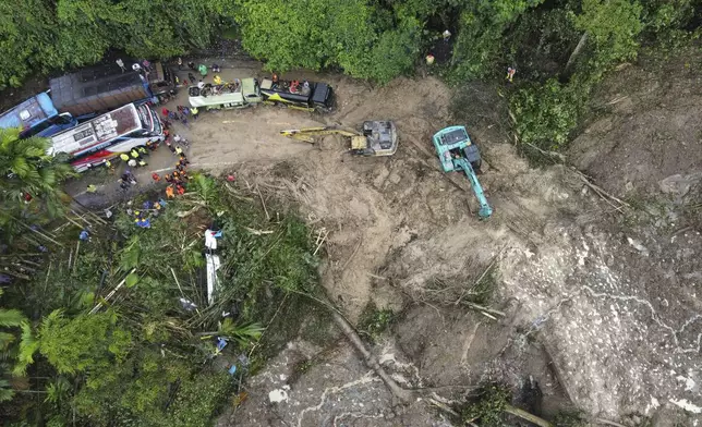 Rescuers use heavy machines to clear mud from a road following a landslide that hit several vehicles and killed multiple people in Deli Serdang, North Sumatra, Indonesia, Thursday, Nov. 28, 2024. (AP Photo/Binsar Bakkara)