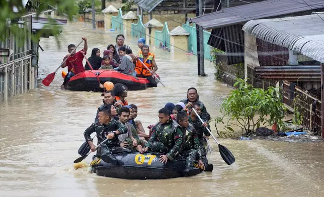 Rescuers use rubber boats to help residents evacuate their homes in a flooded neighborhood following heavy downpours in Medan, North Sumatra, Indonesia, Wednesday, Nov. 27, 2024. (AP Photo/Binsar Bakkara)