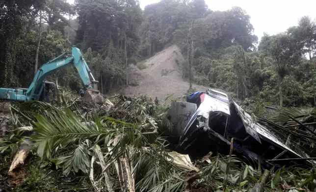 Rescuers use heavy machines to clear mud from a road following a landslide that hit vehicles and killed multiple people in Deli Serdang, North Sumatra, Indonesia, Thursday, Nov. 28, 2024. (AP Photo/Binsar Bakkara)