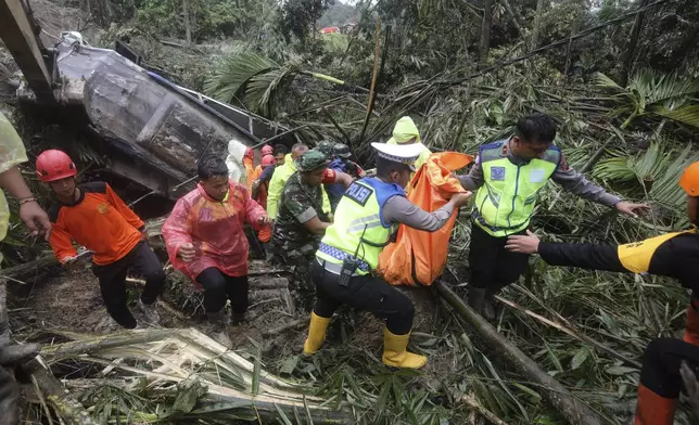 Rescuers remove the body of a victim from the wreckage of a vehicle after it was hit by a landslide that killed multiple people in Deli Serdang, North Sumatra, Indonesia, Thursday, Nov. 28, 2024. (AP Photo/Binsar Bakkara)