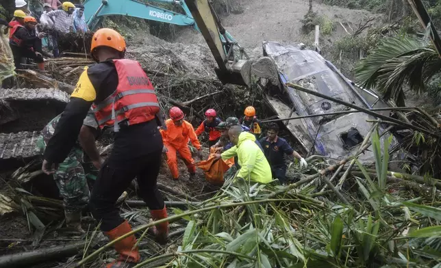 Rescuers remove the body of a victim from the wreckage of a vehicle after it was hit by a landslide that killed multiple people in Deli Serdang, North Sumatra, Indonesia, Thursday, Nov. 28, 2024. (AP Photo/Binsar Bakkara)