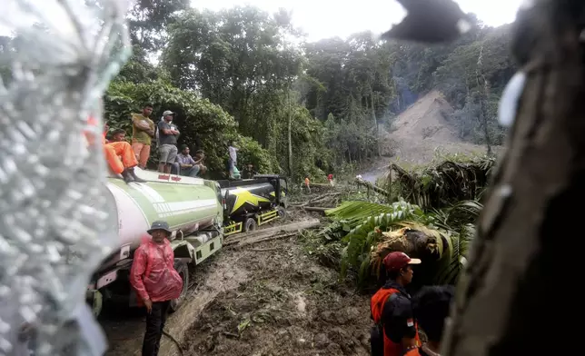 Rescuers and villagers are seen through the wreckage of a vehicle following a landslide that killed multiple people in Deli Serdang, North Sumatra, Indonesia, Thursday, Nov. 28, 2024. (AP Photo/Binsar Bakkara)