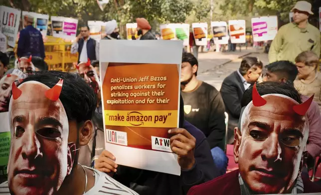 Participants wear paper masks in the likeness of Amazon's Jeff Bezos during a protest by warehouse workers and delivery drivers against the Seattle-based company, demanding higher wages and better working conditions, in New Delhi, India, Friday, Nov. 29, 2024. (AP Photo/Manish Swarup)