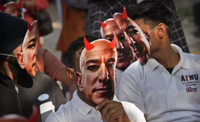 Participants wear paper masks in the likeness of Amazon's Jeff Bezos as warehouse workers and delivery drivers stage a protest against the Seattle-based company demanding higher wages and better working conditions, in New Delhi, India, Friday, Nov. 29, 2024. (AP Photo/Manish Swarup)