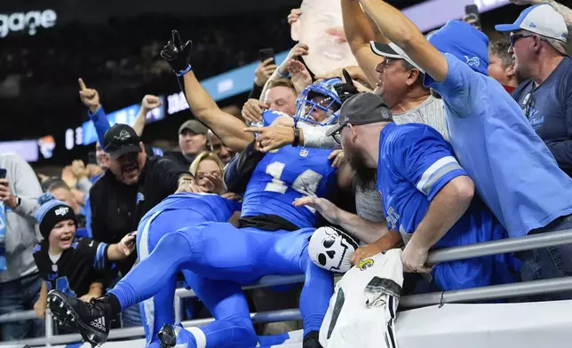 Detroit Lions wide receiver Amon-Ra St. Brown (14) celebrates his nine-yard touchdown reception with fans during the second half of an NFL football game, Sunday, Nov. 17, 2024, in Detroit. (AP Photo/Carlos Osorio)