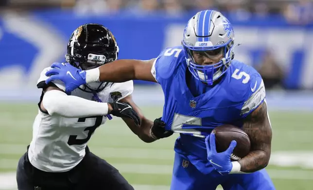 Detroit Lions running back David Montgomery (5) tries to break free from Jacksonville Jaguars cornerback Tyson Campbell (3) during the first half of an NFL football game, Sunday, Nov. 17, 2024, in Detroit. (AP Photo/Duane Burleson)