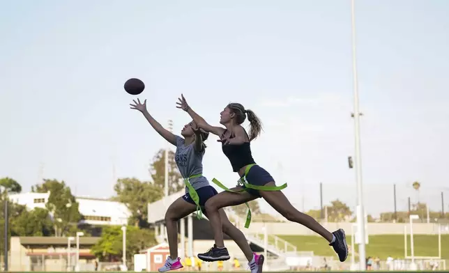 FILE - Syndel Murillo, 16, left, and Shale Harris, 15, reach for a pass as they try out for the Redondo Union High School girls flag football team Thursday, Sept. 1, 2022, in Redondo Beach, Calif. (AP Photo/Ashley Landis, File)