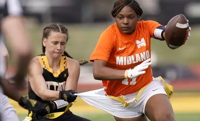 FILE - Ottawa defensive end Jennifer Anthony, left, tackles Midland's JaNasia Spand (11) during an NAIA flag football game in Ottawa, Kan., Friday, March 26, 2021. (AP Photo/Orlin Wagner)