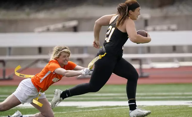 FILE - Ottawa quarterback Madysen Carrera (21) is tackled by Midland defender Casey Thompson, left, during an NAIA flag football game in Ottawa, Kan., Friday, March 26, 2021. (AP Photo/Orlin Wagner, File)