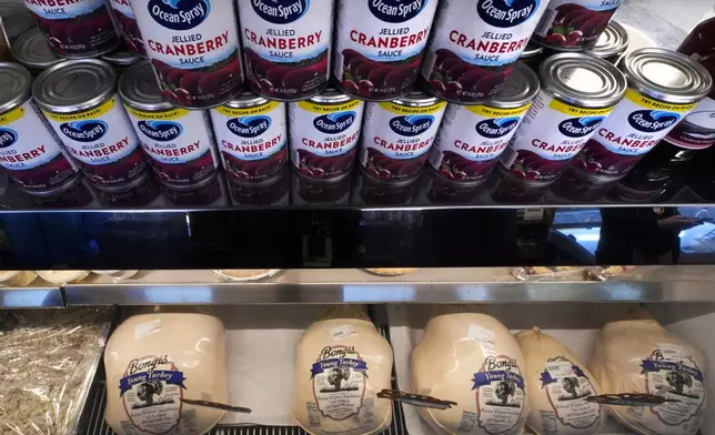 Cans of cranberry sauce line a turkey display case at Bongi's Turkey Roost in advance of the Thanksgiving holiday, Tuesday, Nov. 22, 2022, in Duxbury, Mass. (AP Photo/Charles Krupa)