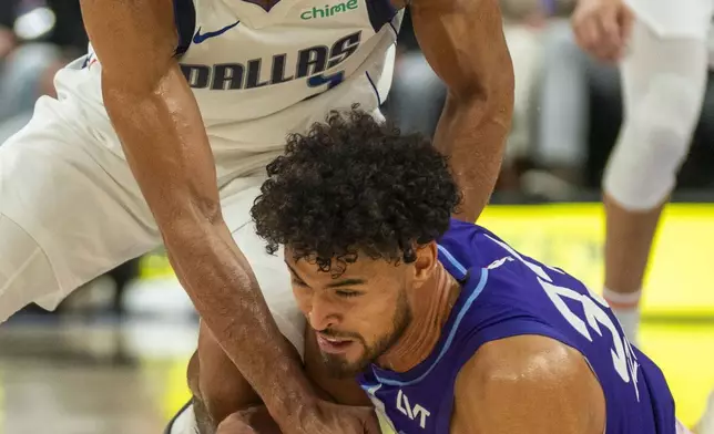 Dallas Mavericks guard Quentin Grimes, top, goes for a loose ball along with Utah Jazz guard Johnny Juzang, bottom, during the first half of an NBA basketball game Thursday, Nov. 14, 2024, in Salt Lake City. (AP Photo/Rick Egan)