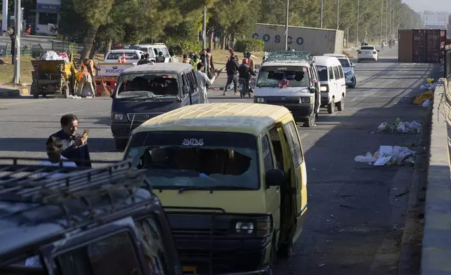 People look at the damaged vehicles left behind by supporters of imprisoned former Prime Minister Imran Khan's Pakistan Tehreek-e-Insaf party when security forces launched an operation Tuesday night to disperse them, in Islamabad, Pakistan, Wednesday, Nov. 27, 2024. (AP Photo/Anjum Naveed)