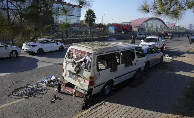 A motorcyclist drives through the damaged vehicles left behind by supporters of imprisoned former Prime Minister Imran Khan's Pakistan Tehreek-e-Insaf party when security forces launched an operation Tuesday night to disperse them, in Islamabad, Pakistan, Wednesday, Nov. 27, 2024. (AP Photo/Anjum Naveed)