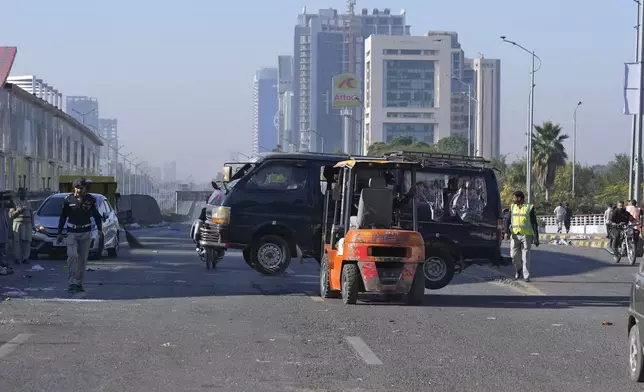 Traffic police officers remove a damaged vehicle left behind by supporters of imprisoned former Prime Minister Imran Khan's Pakistan Tehreek-e-Insaf party, when security forces launched an operation Tuesday night to disperse them, in Islamabad, Pakistan, Wednesday, Nov. 27, 2024. (AP Photo/Anjum Naveed)