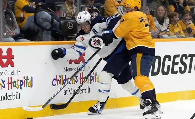 Winnipeg Jets center Mark Scheifele (55) and Nashville Predators defenseman Marc Del Gaizo (7) battle for the puck during the first period of an NHL hockey game Saturday, Nov. 23, 2024, in Nashville, Tenn. (AP Photo/Mark Humphrey)