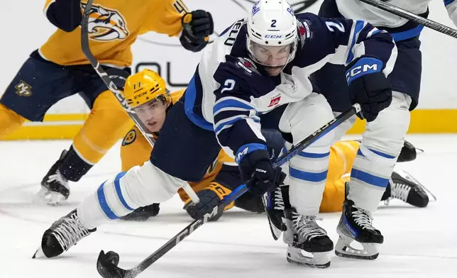 Winnipeg Jets defenseman Dylan DeMelo (2) clears the puck in front of Nashville Predators center Mark Jankowski (17) during the second period of an NHL hockey game Saturday, Nov. 23, 2024, in Nashville, Tenn. (AP Photo/Mark Humphrey)