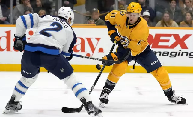 Winnipeg Jets defenseman Dylan DeMelo (2) and Nashville Predators center Mark Jankowski (17) battle for the puck during the second period of an NHL hockey game Saturday, Nov. 23, 2024, in Nashville, Tenn. (AP Photo/Mark Humphrey)