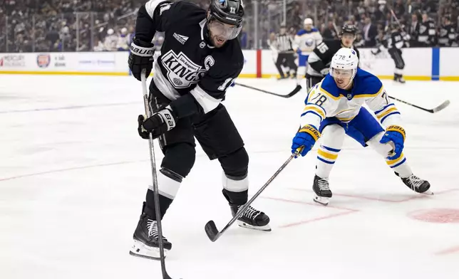 Los Angeles Kings center Anze Kopitar keeps the puck away from Buffalo Sabres defenseman Jacob Bryson during the second period of an NHL hockey game Wednesday, Nov. 20, 2024, in Los Angeles, Calif. (AP Photo/Ryan Sun)