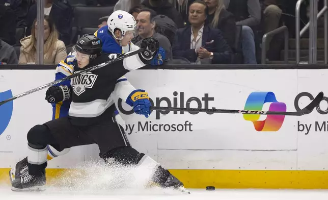 Los Angeles Kings defenseman Jordan Spence, left, and Buffalo Sabres center Jiri Kulich vie for the puck during the first period of an NHL hockey game Wednesday, Nov. 20, 2024, in Los Angeles, Calif. (AP Photo/Ryan Sun)