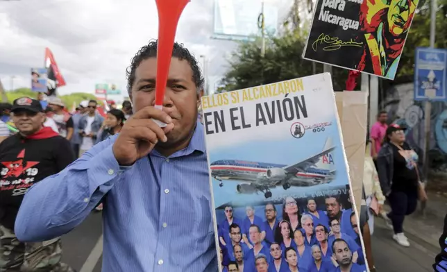 FILE - A supporter of President Daniel Ortega holds a poster with a message that reads in Spanish; "They all fit in the plane", referring to prisoners who were released, stripped of their citizenship and flown to the United States, during a pro-government march in Managua, Nicaragua, Feb. 11, 2023. (AP Photo, File)