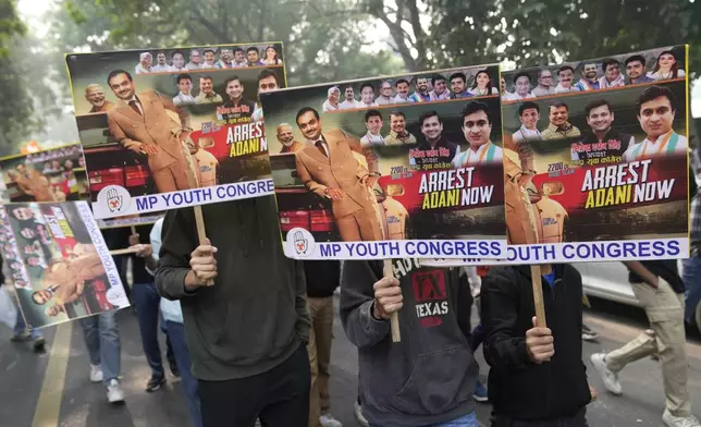 Congress party supporters hold a banners during a protest against Indian billionaire Gautam Adani and Indian Prime Minister Narendra Modi after Adani was indicted by U.S. prosecutors for bribery and fraud, in New Delhi, India, Monday, Nov. 25, 2024. (AP Photo/Manish Swarup)