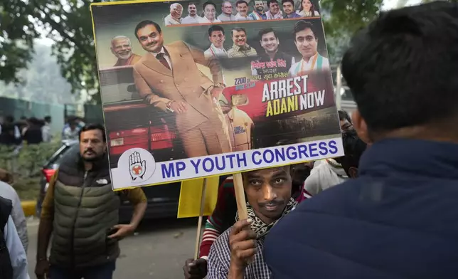 A Congress party supporter holds a banner during a protest against Indian billionaire Gautam Adani and Indian Prime Minister Narendra Modi after Adani was indicted by U.S. prosecutors for bribery and fraud, in New Delhi, India, Monday, Nov. 25, 2024. (AP Photo/Manish Swarup)