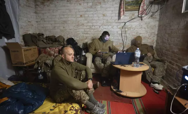 Ukraine's Khartia brigade officer, who goes by callsign Kit, left, sits while his soldiers pilot drones in a shelter on the frontline near Kharkiv, Ukraine, late Thursday, Nov. 7, 2024. (AP Photo/Efrem Lukatsky)