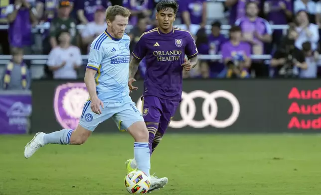 Atlanta United's Dax McCarty, left, moves the ball past Orlando City's Facundo Torres during the first half of an MLS Semifinal Conference playoff soccer match, Sunday, Nov. 24, 2024, in Orlando, Fla. (AP Photo/John Raoux)