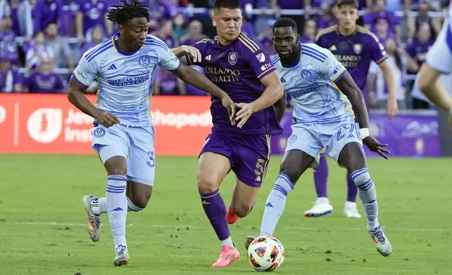 Orlando City's Cesar Araujo (5) tries to move the ball between Atlanta United's Ajani Fortune, left, and Jamal Thiare (29) during the first half of an MLS Semifinal Conference playoff soccer match, Sunday, Nov. 24, 2024, in Orlando, Fla. (AP Photo/John Raoux)