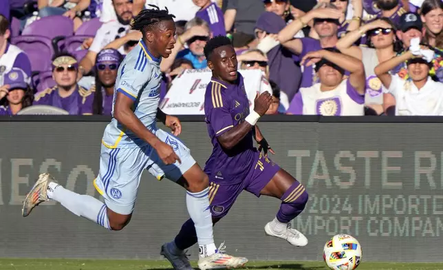 Orlando City's Ivan Angulo, right, moves the ball as Atlanta United's Ajani Fortune, left, defends during the first half of an MLS Semifinal Conference playoff soccer match, Sunday, Nov. 24, 2024, in Orlando, Fla. (AP Photo/John Raoux)