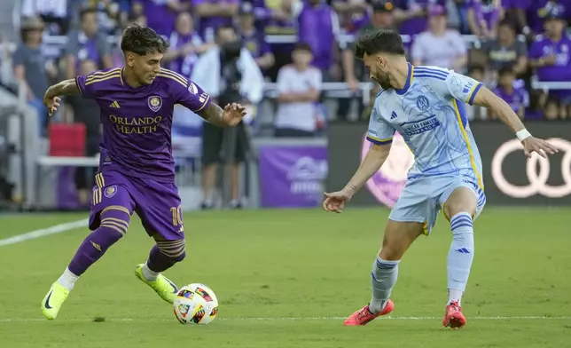 Orlando City's Facundo Torres, left, moves the ball against Atlanta United's Pedro Amador, right, during the first half of an MLS Semifinal Conference playoff soccer match, Sunday, Nov. 24, 2024, in Orlando, Fla. (AP Photo/John Raoux)